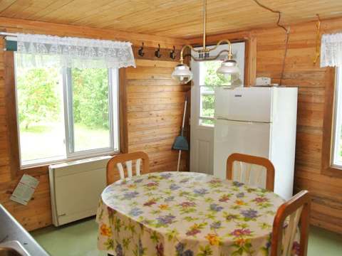 La salle à manger du chalet Le Colibri avec sa table, ses chaises et son réfrigérateur.