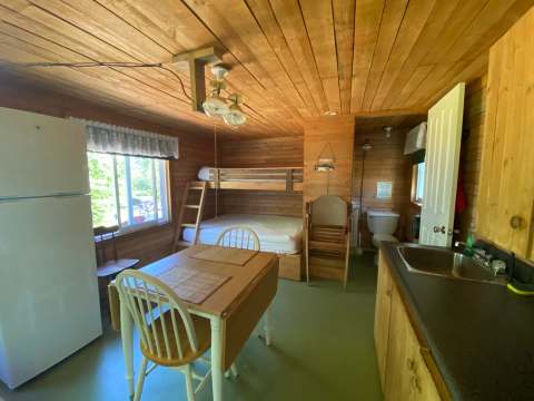 Vue d'ensemble de l'intérieur du chalet incluant la cuisine, la table à manger et les lits.