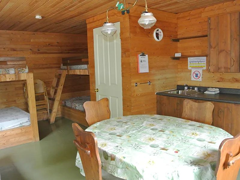 Vue de l'espace de vie comprenant une table à manger et des lits superposés en bois.
