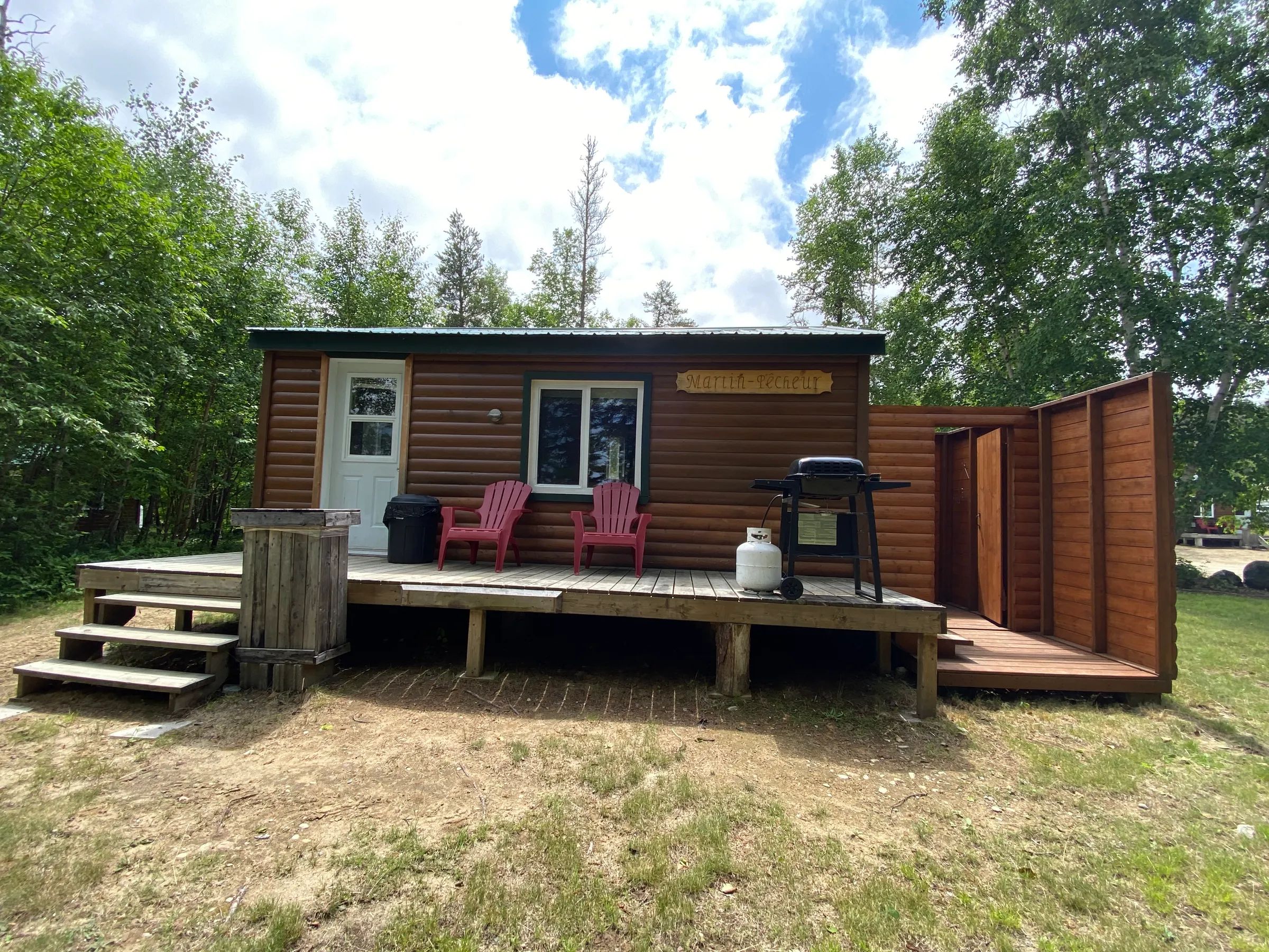The Martin-pêcheur cabin features an outdoor deck with chairs and a barbecue.