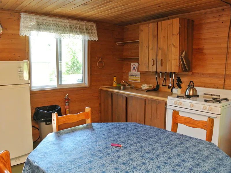 La cuisine fonctionnelle du chalet Mésange comprend une table à manger et les équipements nécessaires.