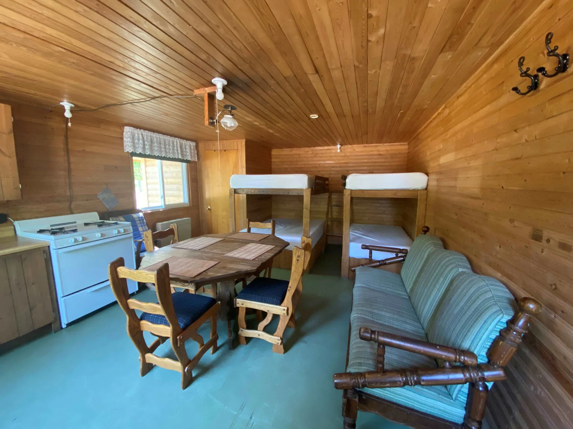Vue d'ensemble de l'intérieur du chalet avec ses lits superposés, sa table à manger et sa cuisinière.