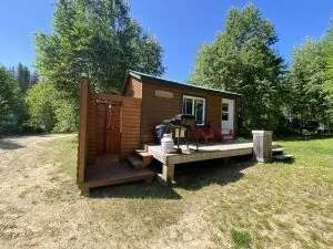 Vue extérieure du chalet Le Colibri avec sa galerie, son barbecue et sa douche extérieure.