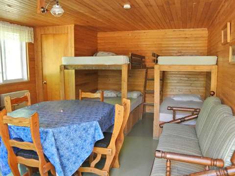 Vue de l'intérieur du chalet avec une table à manger et des lits superposés en bois.