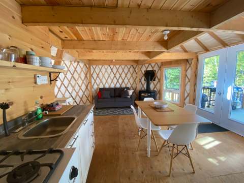 L'intérieur lumineux de la yourte comprend une cuisine équipée, une table à manger et un coin salon.