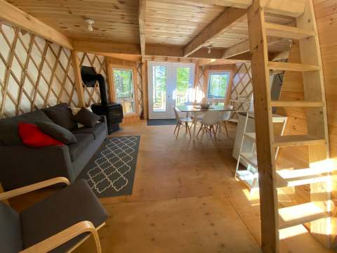 L'intérieur lumineux de la yourte comprend un salon, une table à manger et une mezzanine.