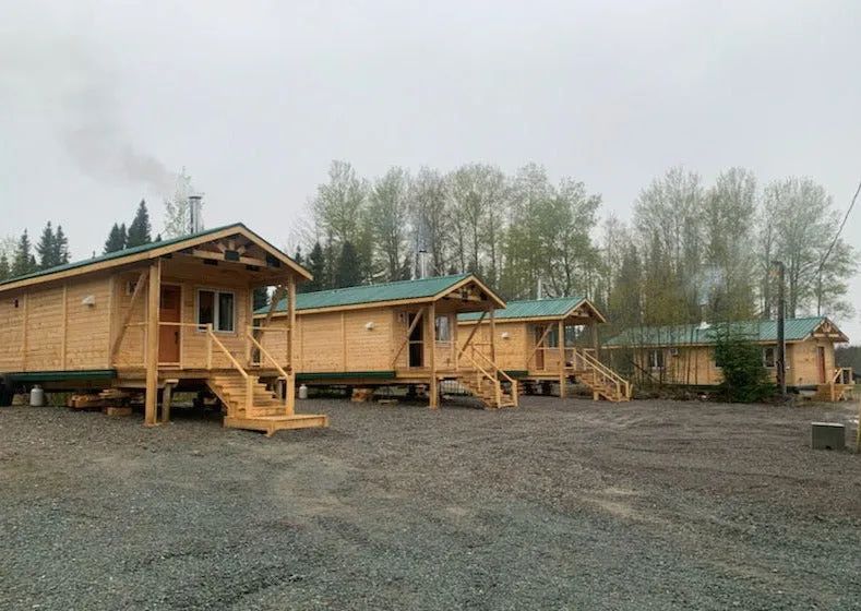 Vue extérieure des chalets en bois situés dans un environnement boisé.