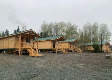 Une rangée de chalets en bois avec toiture verte sur un terrain boisé.