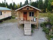 Vue de face d'un chalet en bois avec galerie et escalier d'accès.