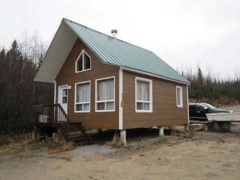 Exterior view of the Le Hibou cabin with its brown siding and green metal roof.