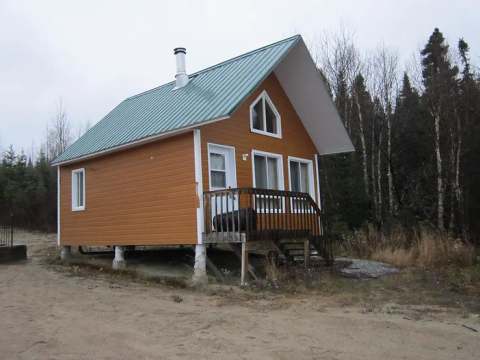 The Hibou cabin is an elevated wooden structure with a green metal roof.