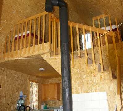 The cottage features a wood stove on the ground floor and a mezzanine equipped with beds.