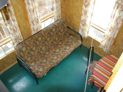 Living area with sofa bed and table in Le Harfang cabin.