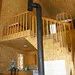 The interior of the cottage features an open area with a mezzanine and a wood stove.