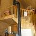 The interior of the cottage features an open area with a mezzanine and a wood stove.