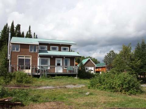 Vue extérieure du chalet Le Grand Duc avec sa galerie en bois et son toit en métal.