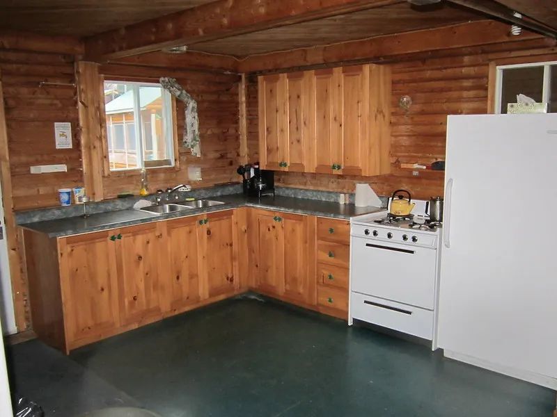 La cuisine en bois équipée comprend une cuisinière et un réfrigérateur dans le chalet Le Grand Duc.