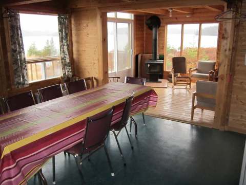 La salle à manger du chalet Le Grand Duc offre une vue panoramique sur le lac et un coin foyer.