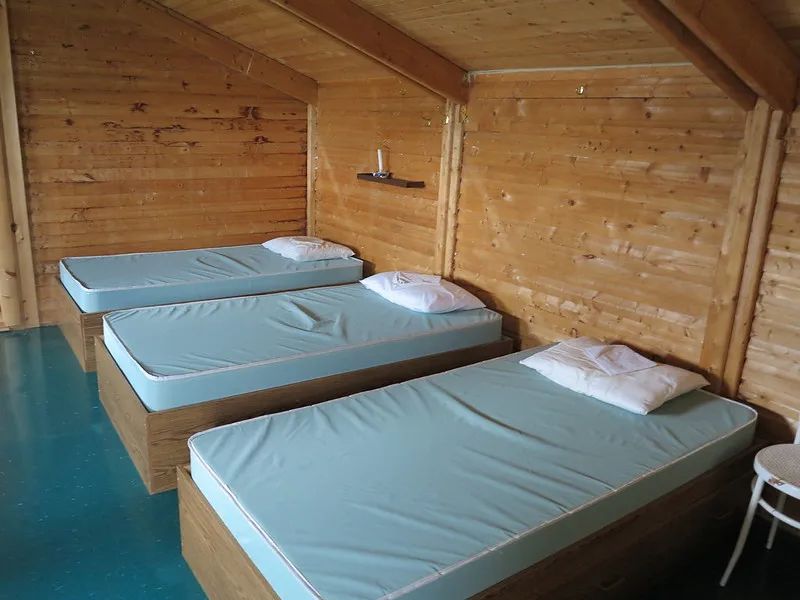 La chambre à coucher du chalet comprend trois lits simples disposés sous un plafond en bois incliné.