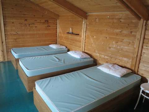 La chambre à coucher du chalet comprend trois lits simples disposés sous un plafond en bois incliné.