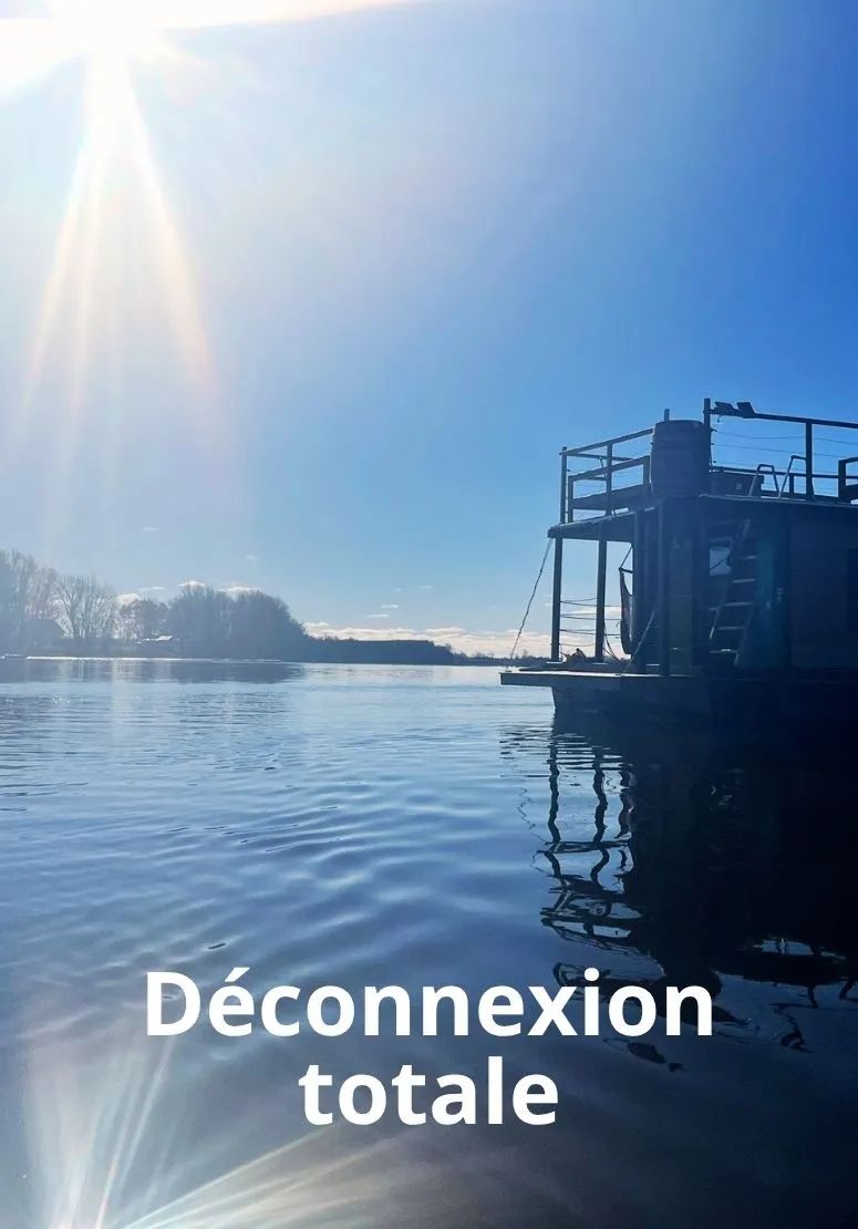 The L'Eau-Tel houseboat is moored on the water on a sunny day.