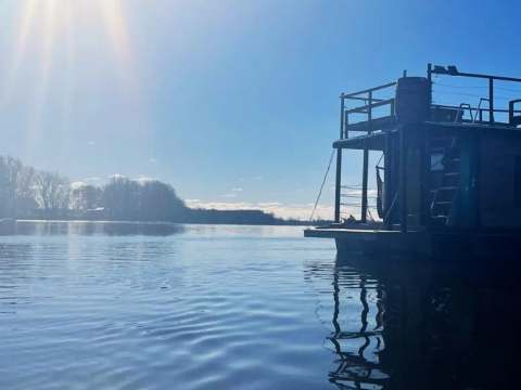 The L'Eau-Tel houseboat is moored on the water on a sunny day.