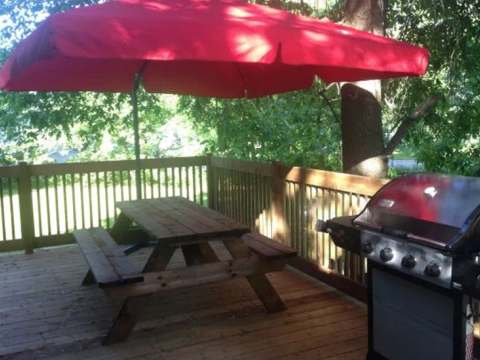 The Bihoreau chalet deck features a picnic table with a parasol and a barbecue grill.