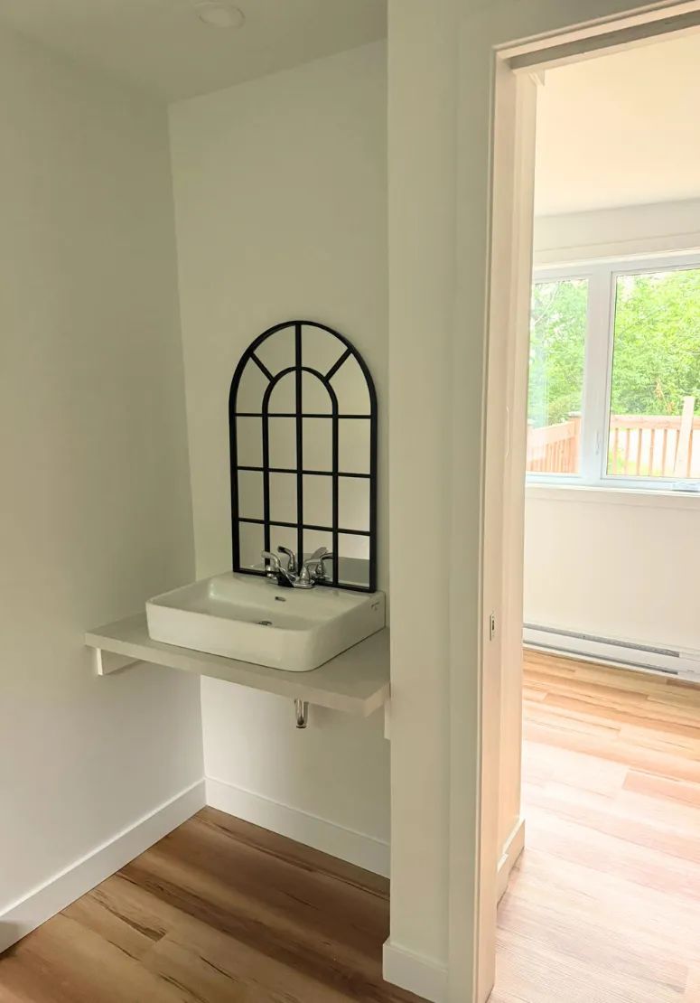 Vue sur le coin lavabo moderne du chalet avec son miroir décoratif.