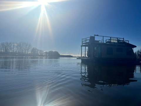Side view of Le Flotteur moored on the water under a sunny sky.