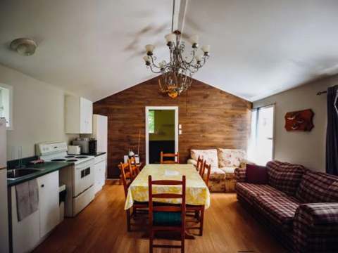 The open-plan cottage area includes an equipped kitchen, a dining table and a cozy living room.