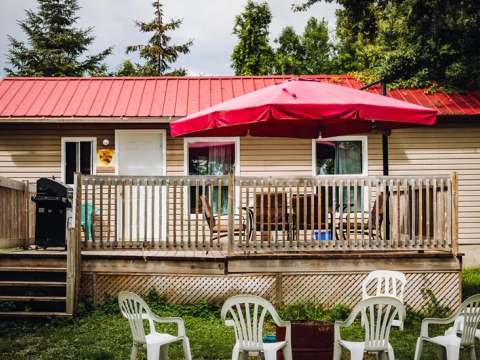 The Chalet Malard deck is equipped with a table, chairs, a patio umbrella, and a barbecue grill.