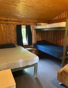 This rustic bedroom in Le Montagnais cottage features a single bed and a bunk bed.