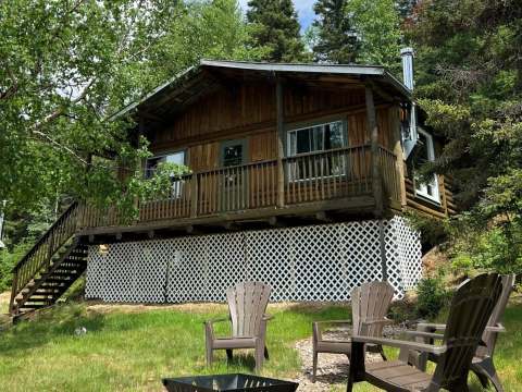 The Montagnais cottage is surrounded by trees and features an outdoor area with a fire pit and chairs.