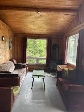 The cottage living room is furnished with comfortable sofas and a wood stove.