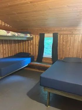 This rustic bedroom in the Le Montagnais cabin is furnished with single and bunk beds.