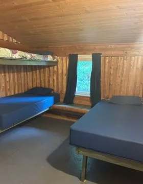 This rustic bedroom in the Le Montagnais cabin is furnished with single and bunk beds.