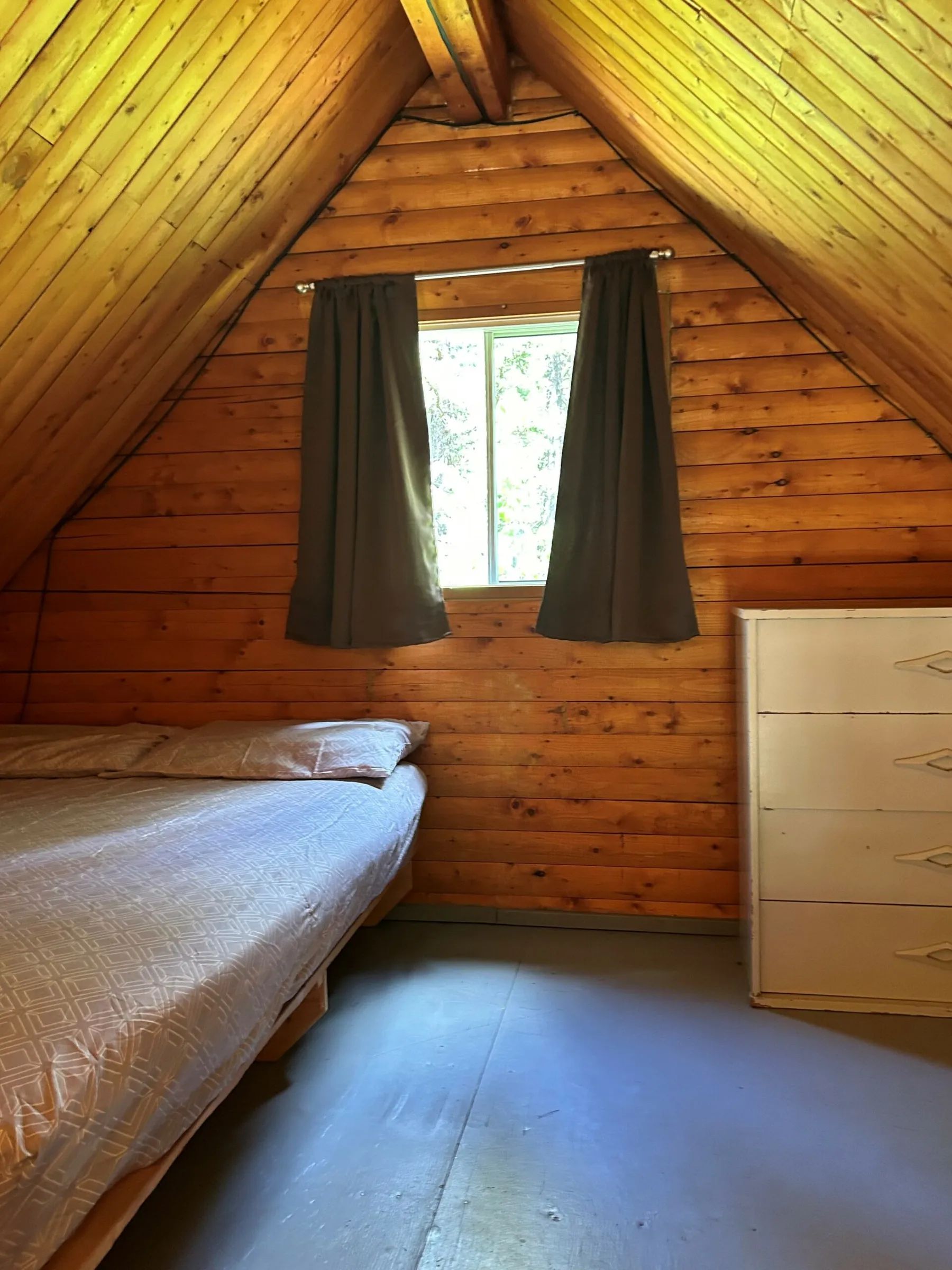 Une chambre confortable sous le toit avec murs en bois rond.
