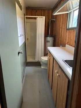 View of the functional bathroom with shower and sink in Le Vieux Camp cottage.