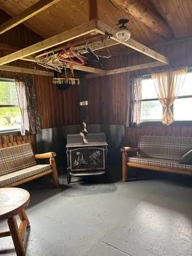 The chalet living area features a wood stove and two rustic wooden benches.