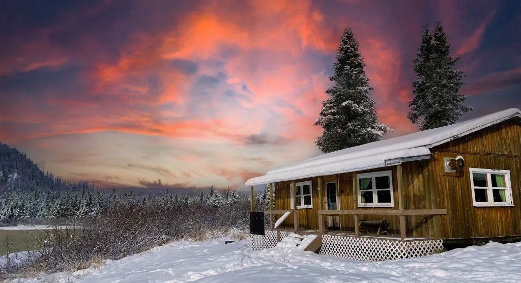Le chalet Le Pêcheur sous un ciel coloré lors d'une journée d'hiver.