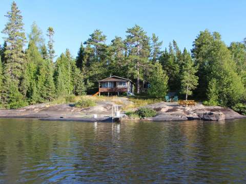 Ce chalet en bois est situé sur le bord de l'eau avec un quai privé et une table de pique-nique.