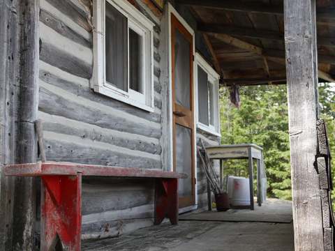 Une vue rapprochée du banc rouge et de la galerie couverte devant le chalet en bois rond.