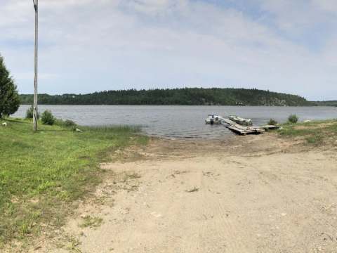 Vue sur le petit chalet situé en bordure de l'eau avec son quai pour les embarcations.