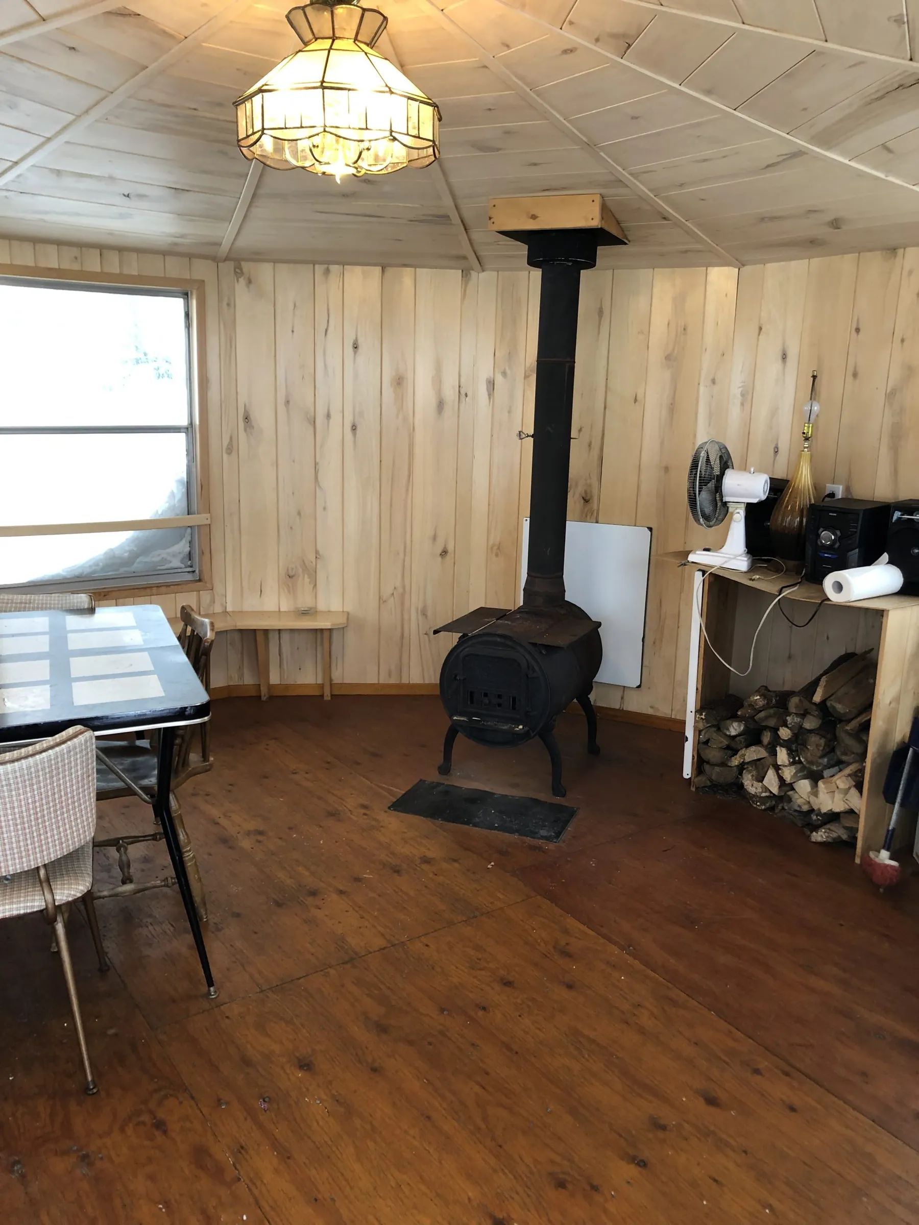 L'intérieur du chalet comporte une table à manger et un poêle à bois pour votre confort.