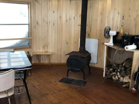 L'intérieur du chalet comporte une table à manger et un poêle à bois pour votre confort.