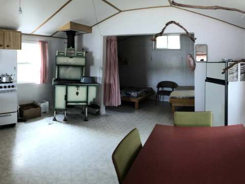 L'espace de vie du chalet comprend une cuisine équipée, un poêle à bois et un coin salle à manger.