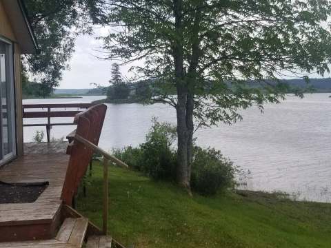 View of the lake from the wooden outdoor deck of the cabin.