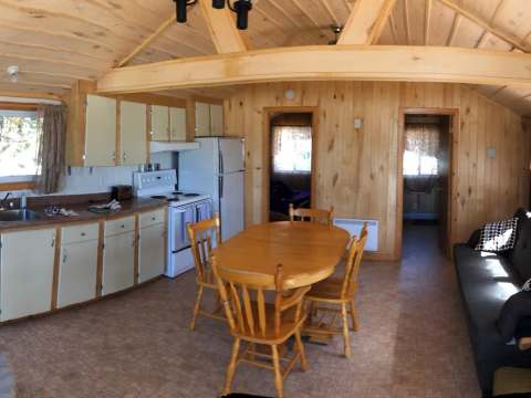 Panoramic view of the open concept area including the equipped kitchen, dining table, and living room.