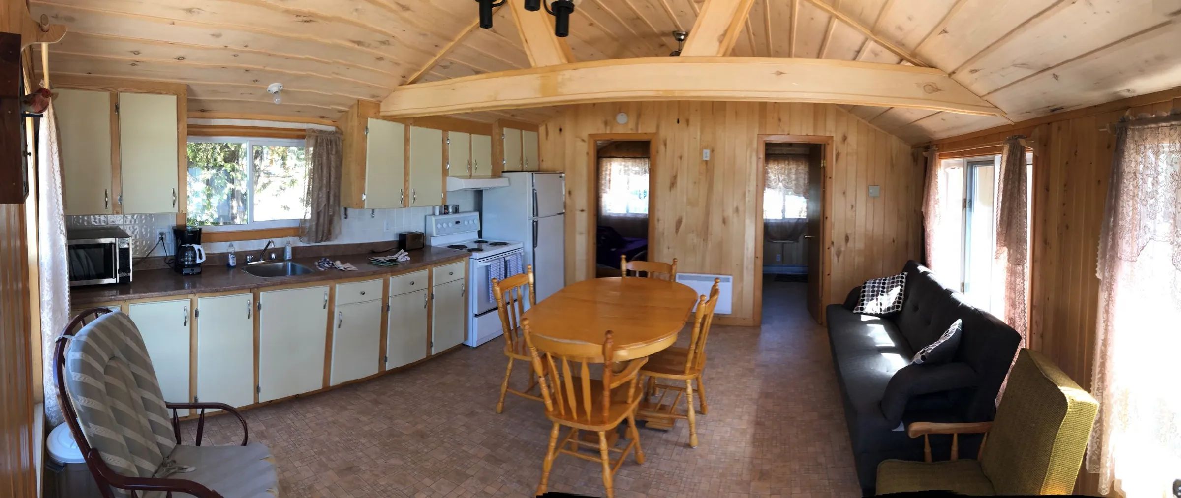 Panoramic view of the open concept area including the equipped kitchen, dining table, and living room.