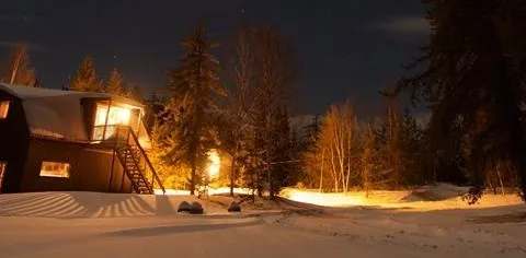 L'Auberge Escapade illuminée dans un paysage enneigé lors d'une soirée d'hiver.